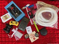 Miscellaneous items including electronics, household goods, and novelty items arranged on a red surface.
