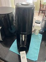 Black SodaStream machine with textured finish and visible carbonating nozzle, placed on a kitchen counter.