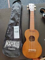 Photo of Mahalo ukulele next to its soft carrying case