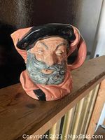 Front angle view of Royal Doulton character jug depicting Sir John Falstaff with detailed facial features and black hat.
