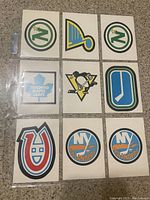 Front side of 9 hockey team logo cards in a 3x3 arrangement, featuring colorful logos from 1977-78 OPC Hockey series.