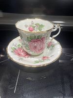 Tea cup and saucer set showing pink rose design and gold rims