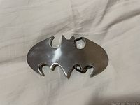 Front view of Batman bat-shaped metal belt buckle, showing smooth silver-tone surface and design