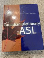 Front cover of the hardcover book titled 'The Canadian Dictionary of ASL' featuring a maple leaf graphic and author names Carole Sue Bailey & Kathy Dolby.