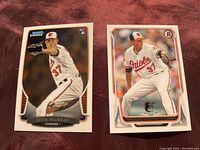 Two Kevin Gausman baseball cards on fabric surface, Left card 2013 Topps/Bowman Chrome #38 Rookie Card, Right card 2014 Topps/Bowman Rated Rookie #179.