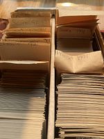 Two cardboard boxes filled with sports cards separated by handwritten paper dividers labeled with brand names and years such as Score 92-93, Classic 92, Pro Set 1991, Score 1991.