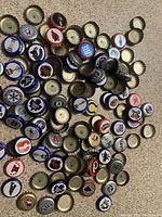 Loose beer bottle caps with various sports team logos like Montreal Canadiens, New York Giants, Tampa Bay Rays spread out on a countertop.