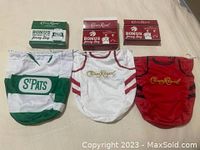 Three cloth drawstring bags resembling sports jerseys with matching Crown Royal bonus jersey bag boxes behind each bag on a bed surface.