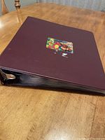 Closed binder containing Pogs with a sticker on the front