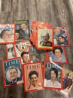 Photo showing a collection of TIME magazines spread out with cover art including prominent 1960s figures, some with illustrated covers and others photographic. Also visible are a few Newsweek magazines.