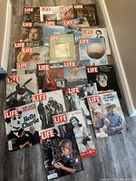 Overview of 17 LIFE magazine issues arranged on floor showing a variety of covers including wartime, political, and cultural topics.