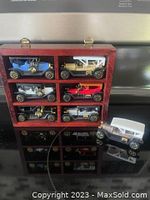 Wooden wall hanging display case with six compartments holding six vintage model cars plus one additional model car outside the case.