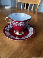 Teacup and saucer set on wooden table, showing front and side of teacup and top of saucer