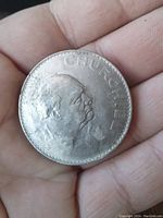 Obverse side of the large coin showing Winston Churchill portrait and inscription 'CHURCHILL'. Held in hand to show size.