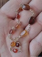 Amber bracelet held in hand showing bead variety and metal links