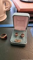 Overview of men's gold ring beside EternaGold box containing earrings