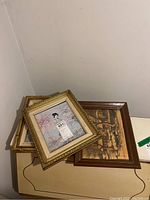 Three smaller framed artworks stacked, showing Asian woman portrait and rustic village scene