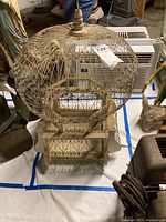 Front view of the vintage bird cage showing the rounded metal wired dome top with heart-shaped and swirling patterns, wooden base with metal decorations and small vase section.