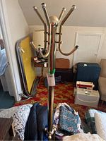 Full view of brass coat hanger stand placed upright, showcasing overall height and multiple hooks for hanging.