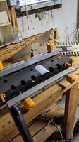 Sears Craftsman industrial deluxe dovetail fixture on a wooden workbench in basement, showing side view with orange adjustment knobs and black fixture base