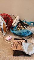 Photo showing Easy Home tabletop fan, white hairdryer, bag with curtain and shower rings, ladies shaver, and other small items on floor.