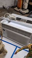 Full front view of LG window air conditioner showing front grill, vents, and power cord neatly wrapped on top.