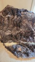 Full view of the dark brown rabbit fur rug displayed on the floor showing patchwork of fur textures and colors.