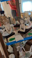 Two mermaid figurines displayed on mirrored shelf with wood bases