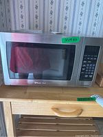 Front view of the silver stainless steel Magic Chef microwave with visible control panel and glass door.