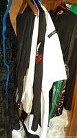 Photo of Navy uniforms hanging on hangers showing black and white uniform pieces with rank patches and insignia