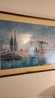 Framed Victorian bridge print over water with blue sky and trees, behind glass