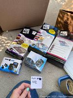 Photo showing 2 dash cams in retail boxes alongside 3 boxed Space Bag storage bags on pavement next to cardboard box.