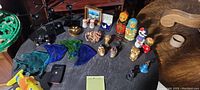 Photo showing the full variety of decorative items including Matryoshka dolls and animal figurines on a black table.