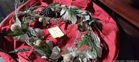 Decorative holiday wreath with pinecones, faux greenery, and round ornamental balls with a frosted finish.