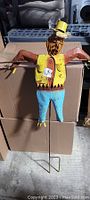 Front view of colorful metal scarecrow showing its rusted condition and detailing