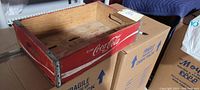 Top view of the vintage Coca Cola wooden crate showing red exterior, metal corner supports, interior slats with slots and handgrips.