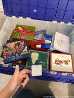 Open plastic tote filled with assorted ornament boxes of various colors and designs