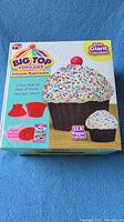 Box image showing colorful packaging of Big Top Cupcake Silicone Bakeware with claims of making giant cupcakes 25 times bigger