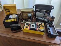Overview of six vintage cameras with cases and accessories on table
