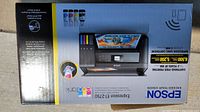 Photo of Epson ET-2750 EcoTank Printer box showing product image, ink tanks, and key features including wireless printing and cartridge-free printing for 2 years.