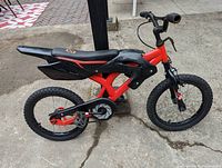 Side view of the kids bike showing the black and red motobike-inspired frame, tires, and detail.