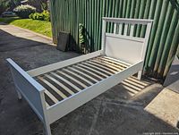 Assembled bed frame angled view showing headboard, footboard, side rails, wooden slats