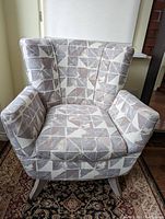 Front view of the occasional chair showing geometric upholstery pattern and wooden rocker legs