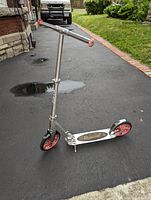 Full view of Razor scooter showing adjustable handlebar, deck, and wheels on pavement outdoors.