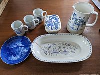 Full set displayed including blue and white pitcher, rectangular dish, long oval bowl, three small mugs, and collectible plate