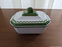 Top view of closed casserole dish showing green handle knob on lid and green wavy trim border.