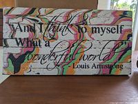 Front view of the wooden sign with painted quote and colorful marbling.