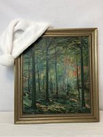 Frontal view of framed oil painting with white fabric draped across top left corner