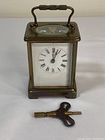 Full front view showing clock case, dial and key placed in front