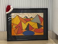 Frontal view of framed lithograph leaning against corrugated metal storage wall